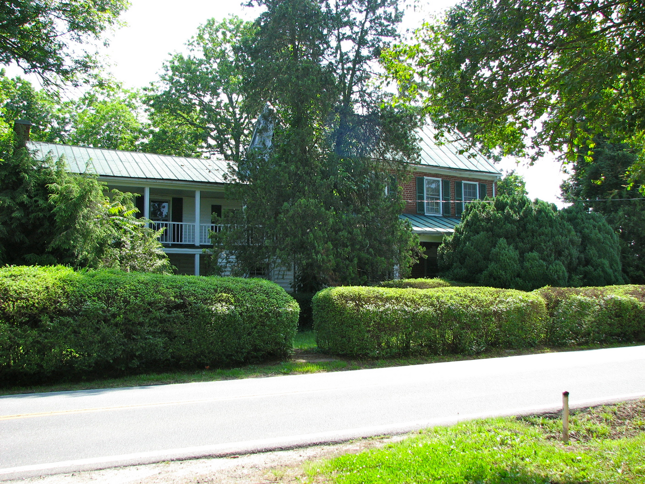 Andrew’s Tavern behind hedges beside a road
