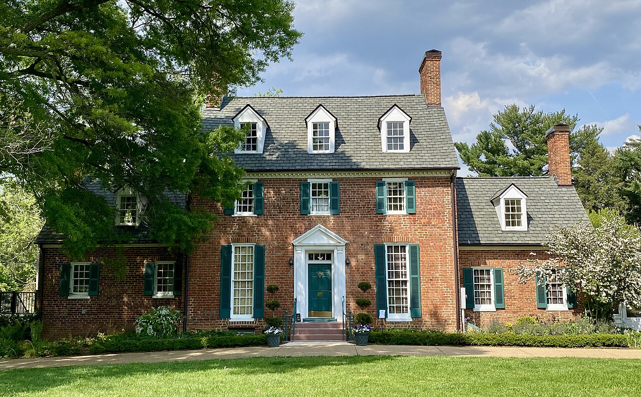 Brick Green Spring house framed by garden trees