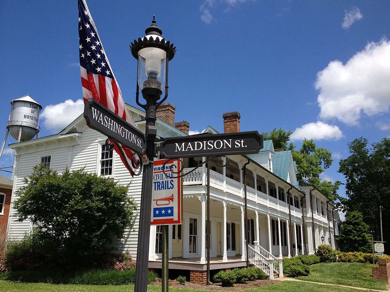 Long porch of Boyd Tavern beside street signs in Boydton