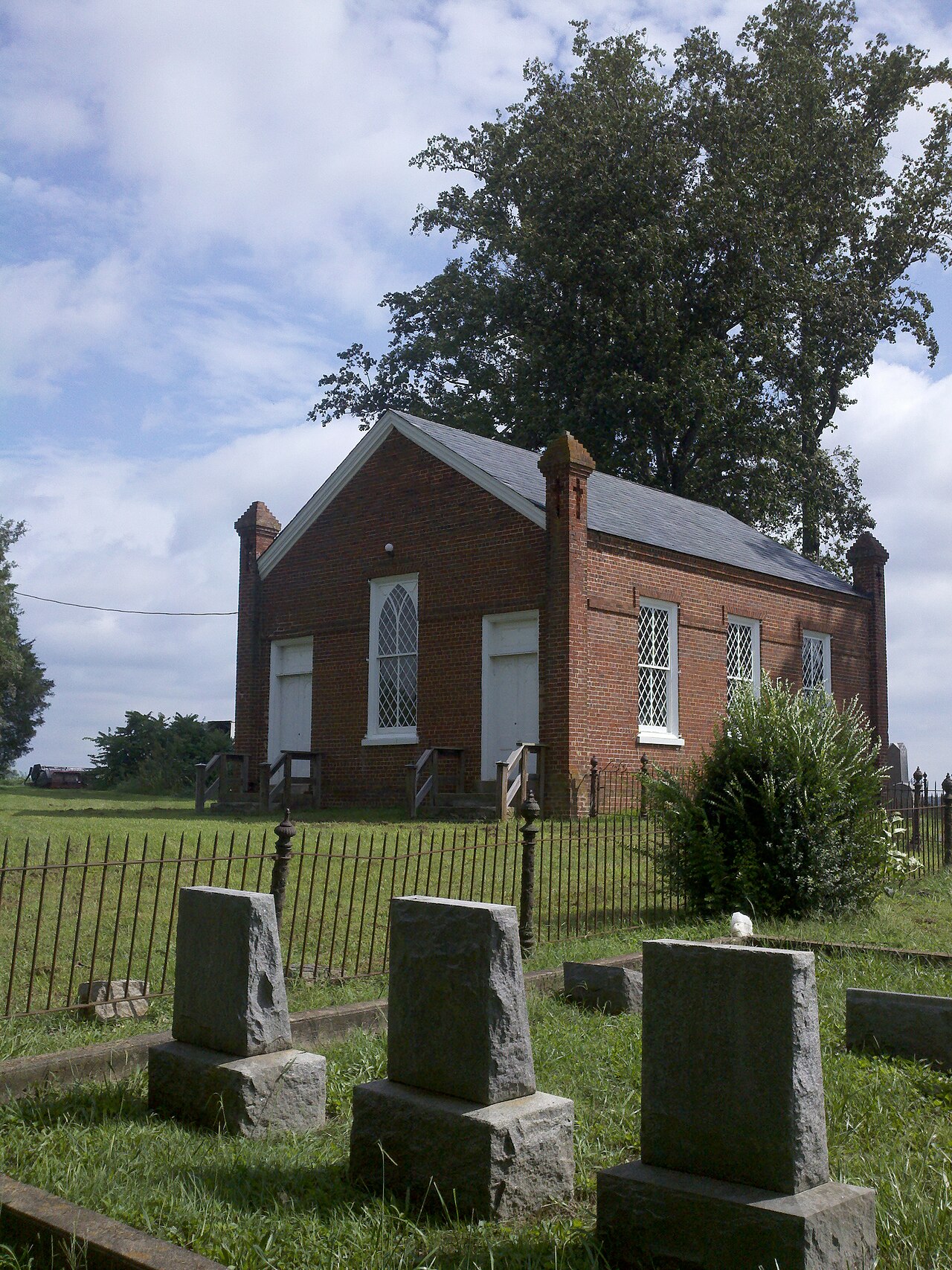 Grub Hill Church and gravestones beside a brick wall